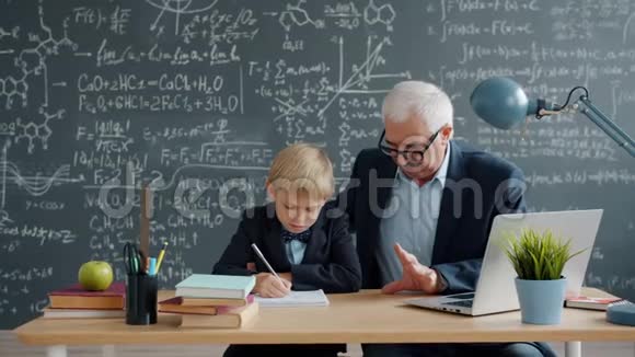 成熟的男老师在大学教室里教小聪明的男孩忙于教育视频的预览图