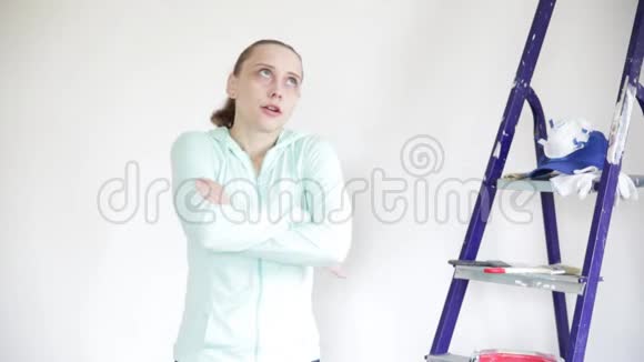 一个年轻的女人靠在一堵白色的墙上情绪地滚动着她的眼睛张开双臂不高兴地摇摇头视频的预览图