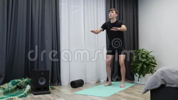 健身教练确实在室内蹲运动自信的人在家做深蹲练习年轻健康的男性蹲在瑜伽垫上视频的预览图