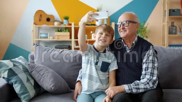 开朗的老人用智能手机相机和可爱的小孙子自拍视频的预览图