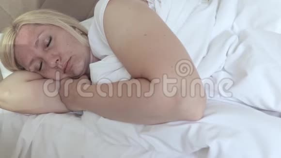 睡意朦胧的中年妇女躺在床上揉着眼睛和脸试图醒来视频的预览图