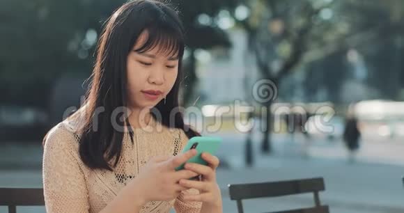 带着智能手机坐在长凳上的女孩视频的预览图