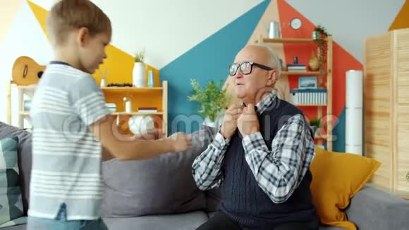 照顾孩子的小男孩帮老人穿衣服然后在家里玩视频的预览图