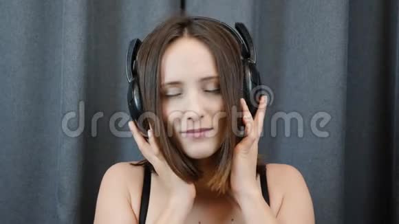 带着耳机的性感女人肖像镜头害羞的女性闭着眼睛听音乐微笑着对着镜头快乐女孩视频的预览图