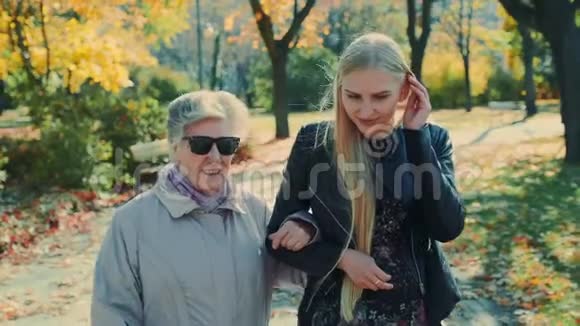 秋天公园里一位老妇人和一个快乐的金发女孩走在一起视频的预览图