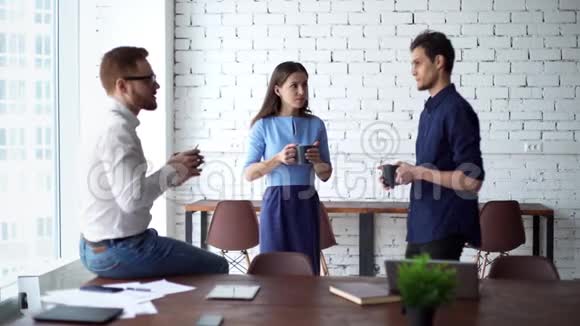 三个友好的同事站在办公室喝咖啡聊天视频的预览图