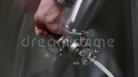 一名男性啤酒商的特写镜头打开一个水龙头将啤酒从啤酒罐分配到桶中视频的预览图