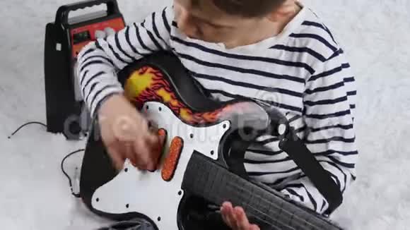 一个小男孩用电吉他演奏音乐幼儿在琴弦上演奏主动节奏一张脸视频的预览图