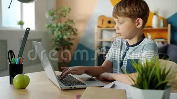 认真的男孩在家里用笔记本电脑然后在家里做笔记学习视频的预览图