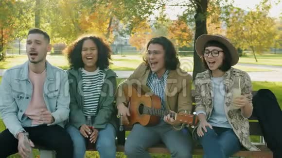 快乐的朋友的肖像男人和女人弹吉他在户外唱歌视频的预览图