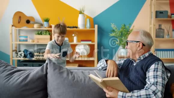 玩耍的孩子和慈爱的祖父在家里读书的时候正在做着高五视频的预览图