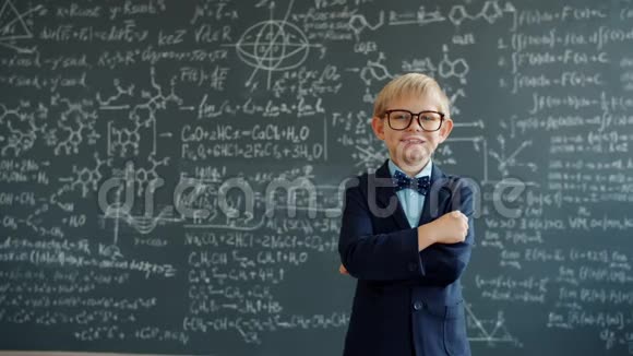 穿西装戴眼镜的快乐小朋友站在教室里背景是黑板视频的预览图
