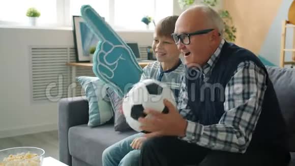 欢乐的家庭祖父和孙子在电视上看足球欢呼视频的预览图