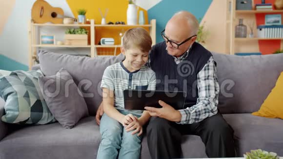 孙辈和孙子在家里用平板电脑慢动作笑着说话视频的预览图