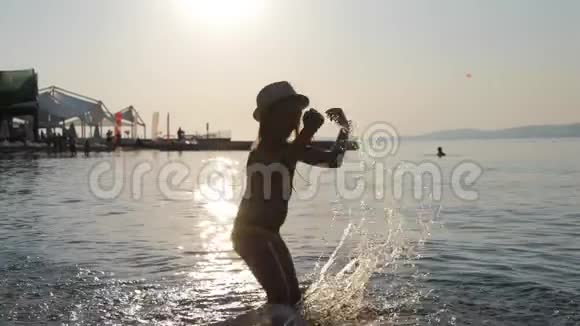 年轻女孩日落时在海洋上玩耍的剪影暑假积极情绪视频的预览图