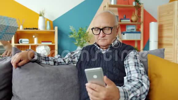 祖父使用智能手机时孙子送礼物盒祝贺在家视频的预览图