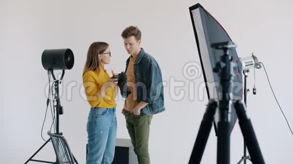 女孩和男人模特在工作室里看照片讨论拍照环节视频的预览图