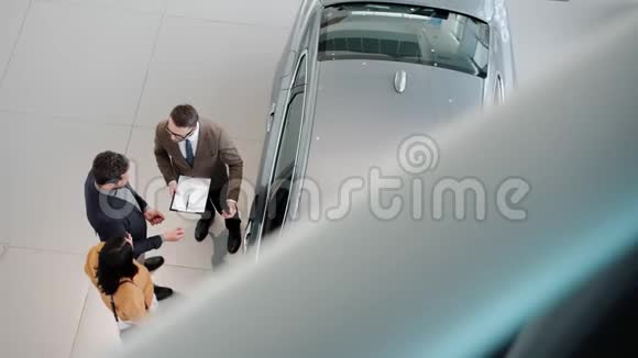 从高角度看年轻家庭买车与销售员握手拥抱视频的预览图