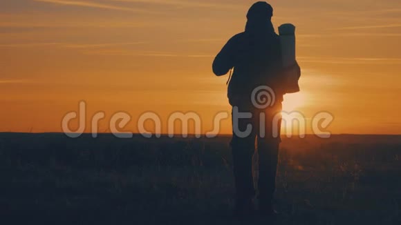 一个背着背包的男人在明亮的天空日落时的剪影太阳下山了旅行概念慢视频游客视频的预览图