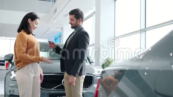 帅哥把车钥匙给了经销商的兴奋女人拥抱着微笑视频的预览图
