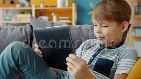 带着微笑的孩子在公寓里拿着平板电脑看视频的慢动作视频的预览图