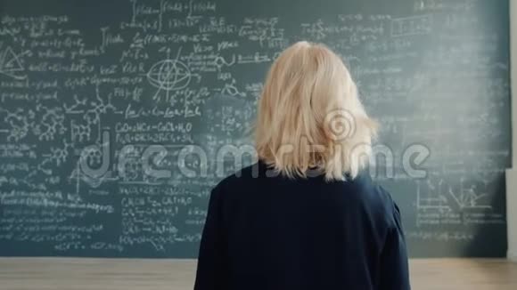 女科学家在大学教室里用公式走到黑板墙上视频的预览图