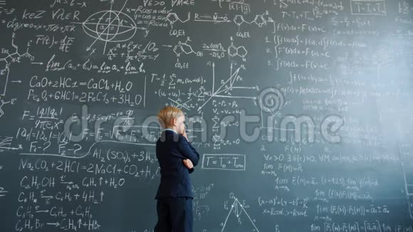 小男孩在想在大学里看黑板上写的公式视频的预览图