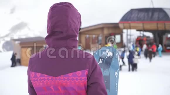 在滑雪场女孩滑雪者手里拿着滑雪板雪山上的运动女人滑雪冬季阳光明媚视频的预览图