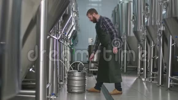 一个长着胡子的男酿酒师把一个桶和一个啤酒罐连接起来然后装满啤酒视频的预览图