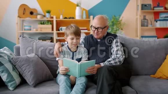老人爷爷在公寓里给聪明的孙子读书视频的预览图
