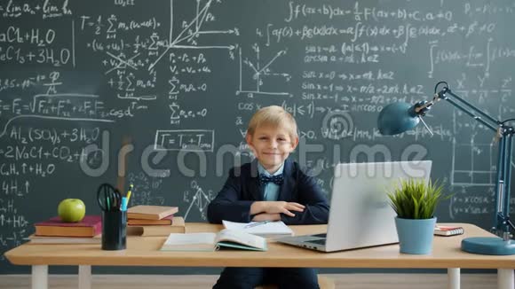 学校课桌上微笑的聪明男孩的肖像背景是带有公式的黑板视频的预览图
