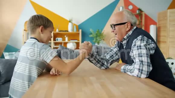 快乐的孩子在公寓里和有爱的祖父摔跤视频的预览图
