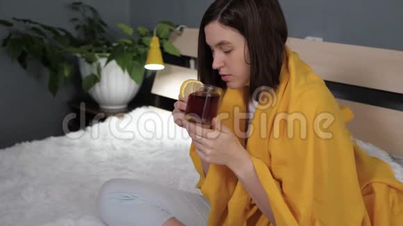 女孩在喝红茶迷人的年轻女人生病了坐在床上喝柠檬茶感冒流感视频的预览图
