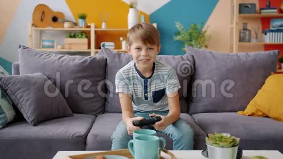 快乐男孩独自在家舒适的沙发上玩电子游戏的画像视频的预览图