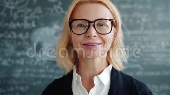 大学班室内有魅力的成年女教授对着镜头微笑的画像视频的预览图