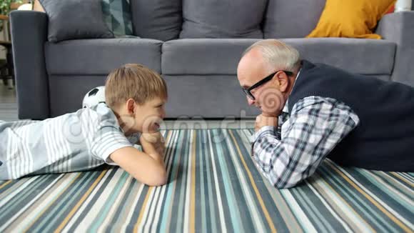 祖父和孙子在家里地板上说话时动作缓慢视频的预览图