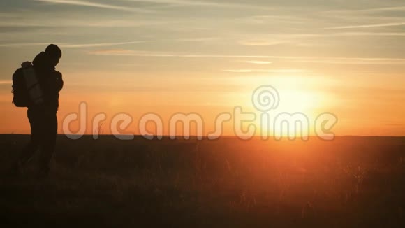 剪影孤独的人背着背包在山里在夕阳和夕阳下散步旅游概念视频的预览图