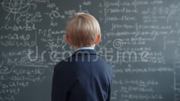 穿西装的小男孩走在黑板墙上用公式思考视频的预览图