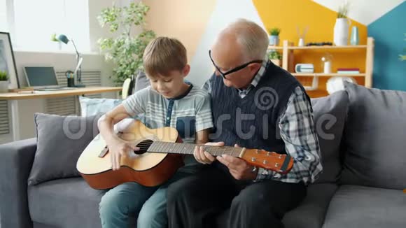 快乐的人孙子和爷爷在家弹吉他的慢动作视频的预览图
