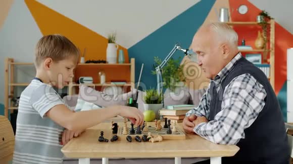 快乐的孩子和祖父下棋赢了做着击掌大笑视频的预览图
