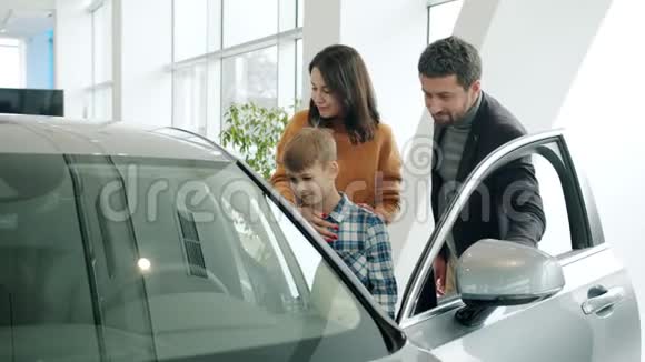 母亲父亲和儿子买了一辆汽车在展厅里享受着新汽车的乐趣视频的预览图