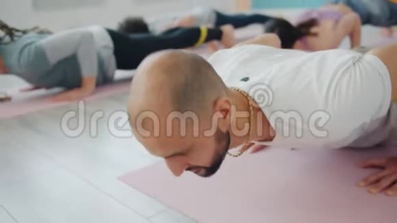 在瑜伽课室内锻炼的大胡子年轻女人在垫子上活动视频的预览图