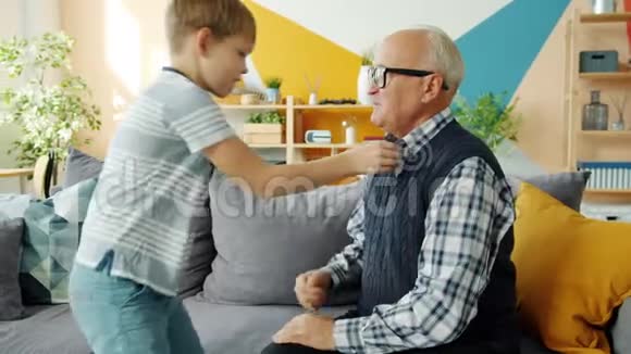 帮助孙子帮助祖父穿衣服在家玩得很开心视频的预览图
