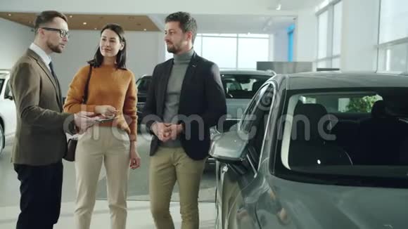 在汽车经销商与经理交谈时夫妻双方购买车辆视频的预览图