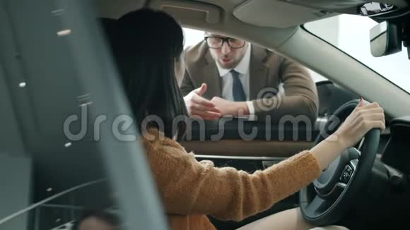 年轻的女商人正在谈论汽车经销商坐在新汽车室内视频的预览图