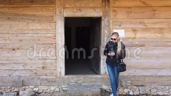 在一个老村庄的木屋附近使用手机的女人视频的预览图