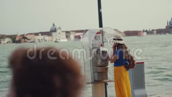 戴帽子的女士带旧公用电话的黄色短裙视频的预览图