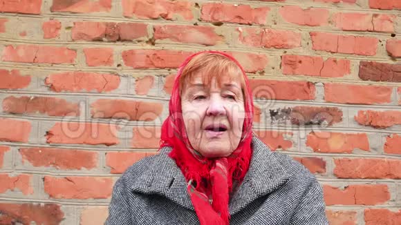 戴着红领巾的老妇人在砖墙背景上视频的预览图