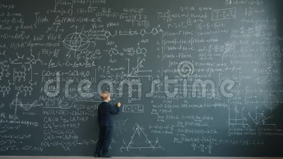 身材魁梧的孩子在学校教室的大黑板上写公式视频的预览图
