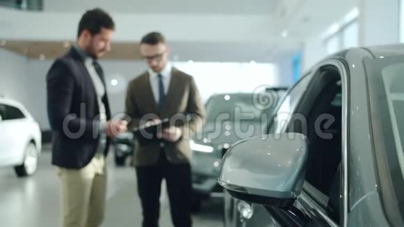 商人与销售经理交谈在当代展厅选择汽车关注车辆反光镜视频的预览图